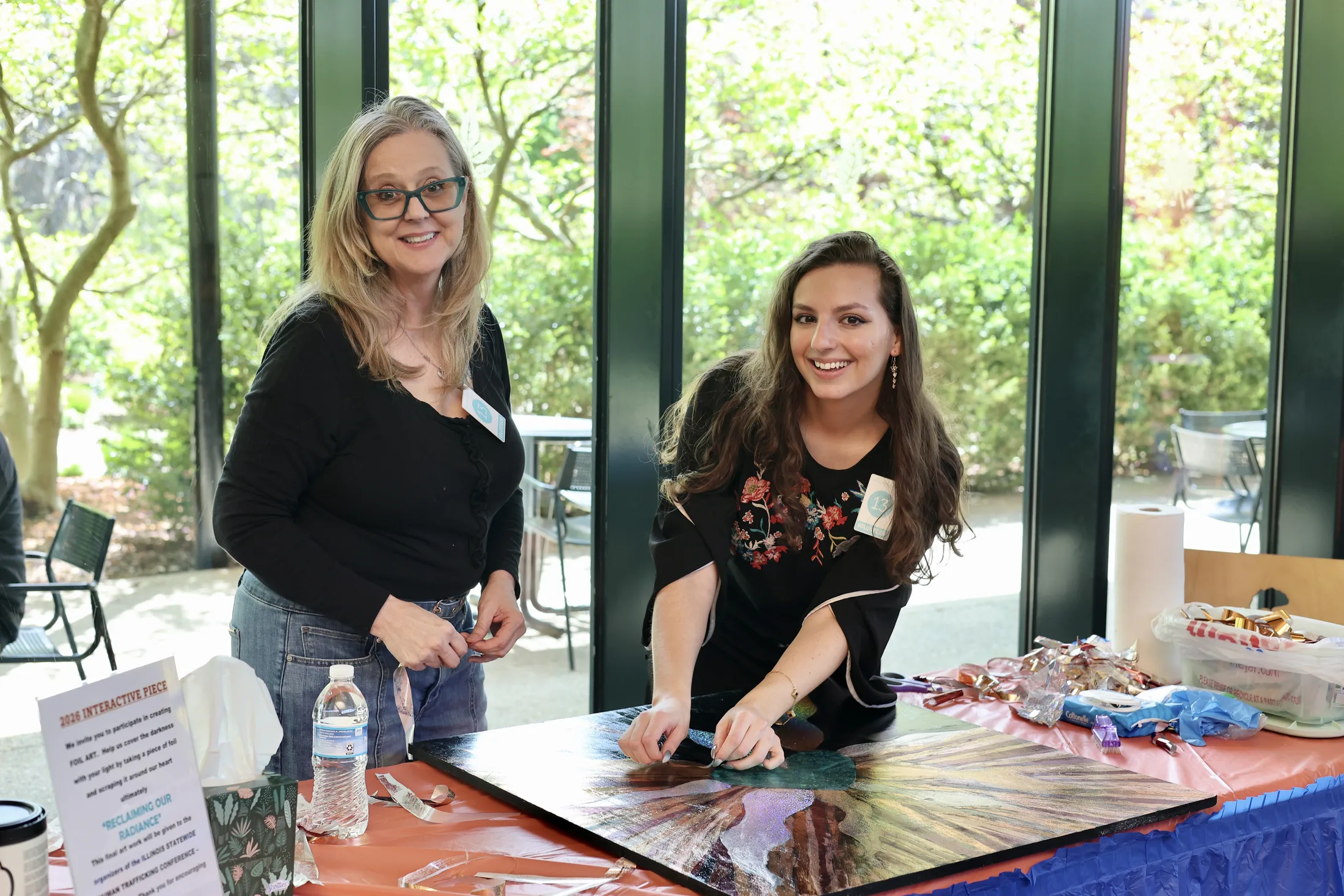 Two Reclaim 13 event organizers standing near an art table